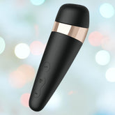 The Satisfyer Pro 3+ Air Pulse Stimulator by Satisfyer is a stylish black device accented with gold, featuring side control buttons and an innovative conical design. Against a softly blurred background with pastel bokeh lights, it exudes premium elegance and functionality.